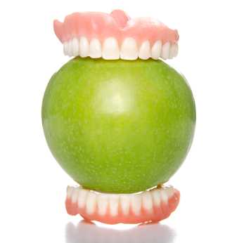 Dentures biting a green apple